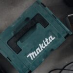 Ein ruhig arbeitender Makita Laubbläser liegt auf einer Wiese, umgeben von einem entspannten Hund und einer Katze, die sich nicht gestört fühlen.